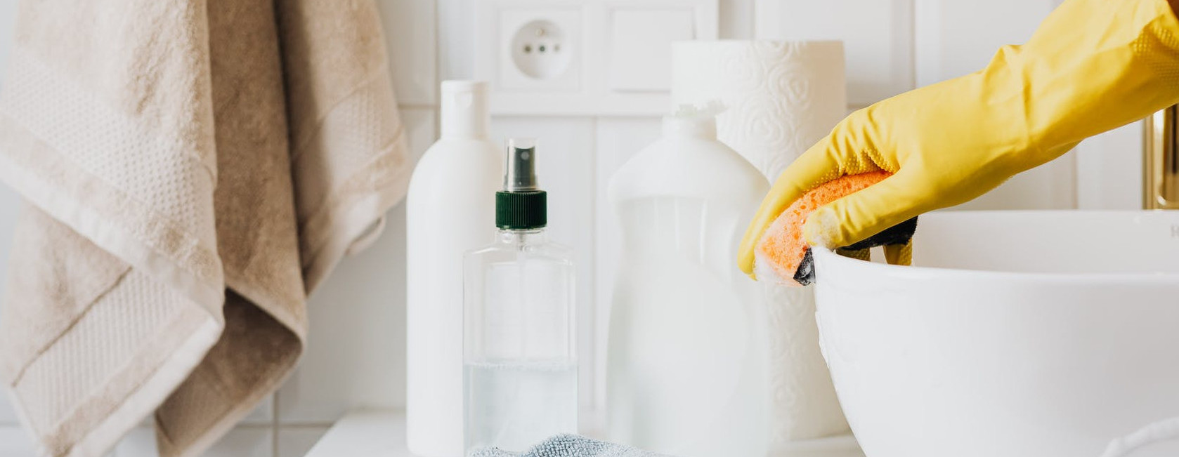 Folded towels beside cleaning products in a bathroom